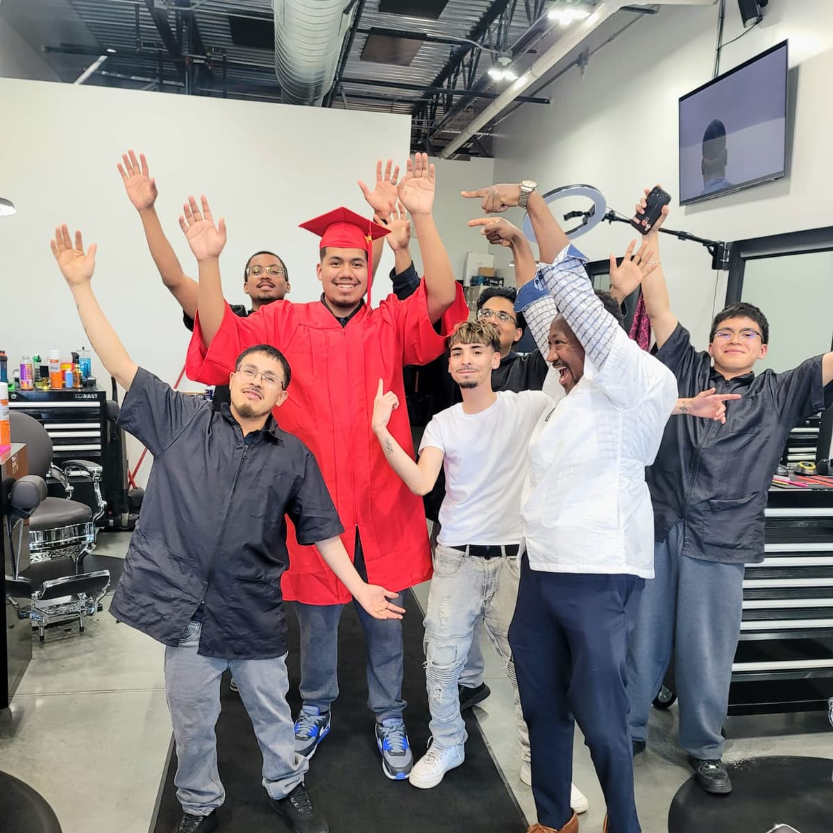 Marvelous Barber School graduates and supporters cheering together on the clinic floor.