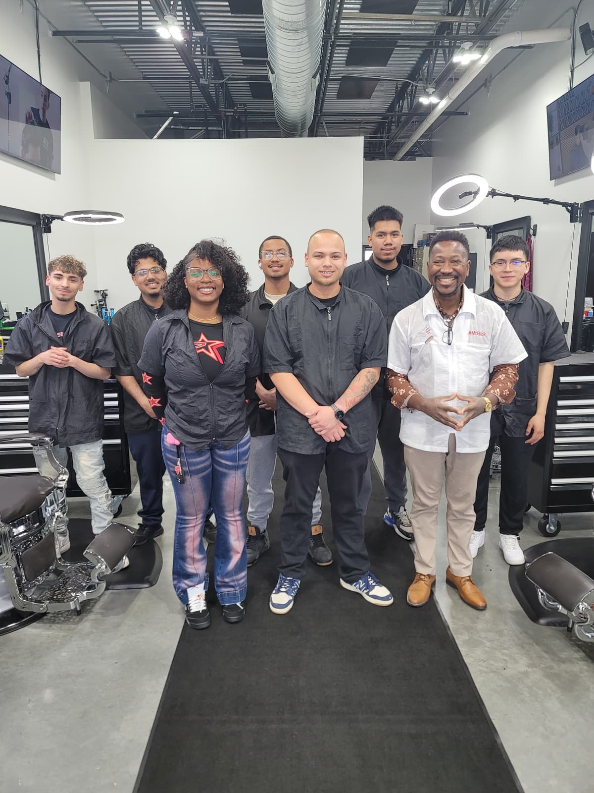 Marvelous Barber School alumni lined up with Mr. Rick in the clinic after final evaluations.