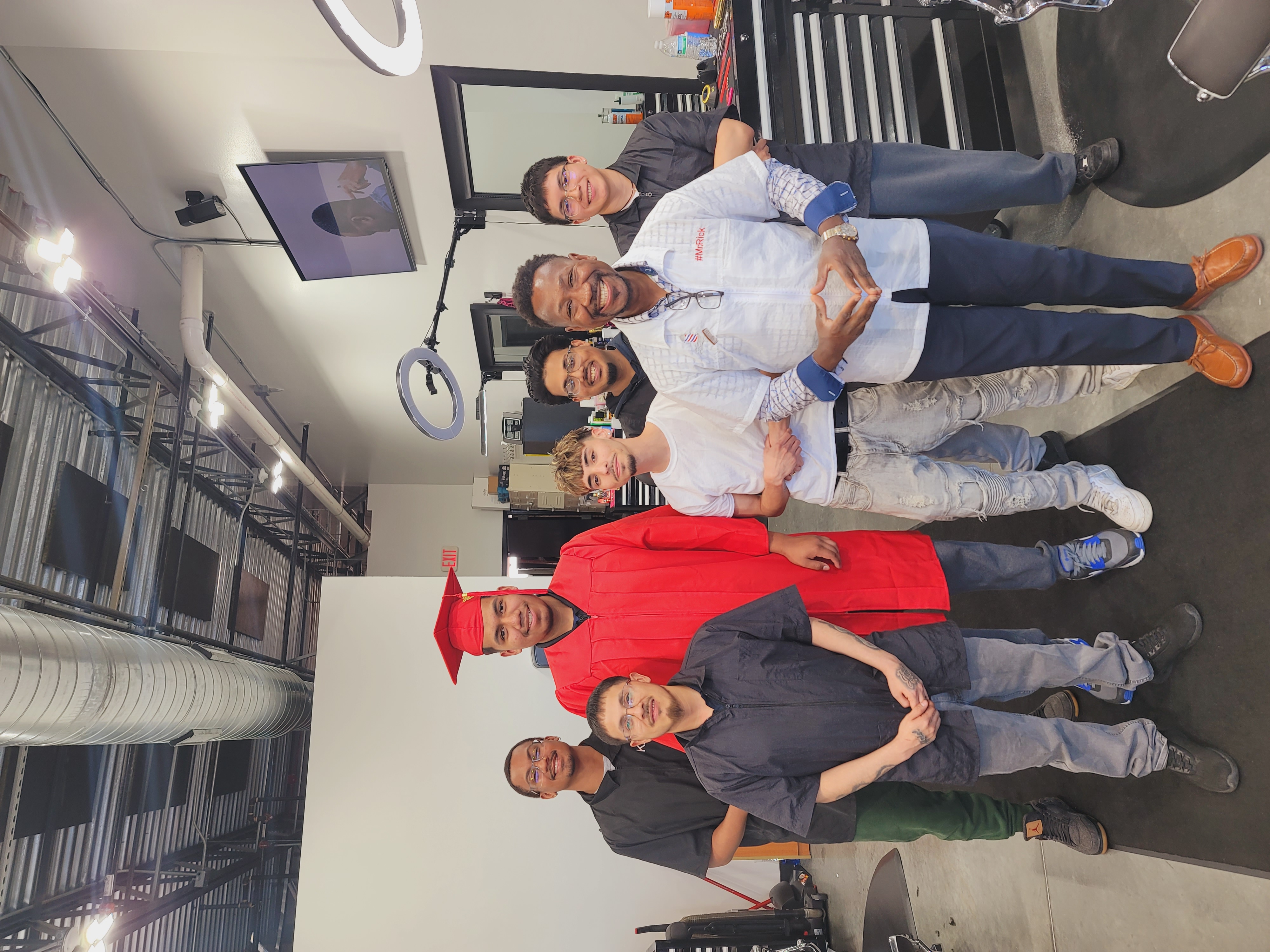 Mr. Rick standing with a Marvelous graduate and classmates inside the studio.